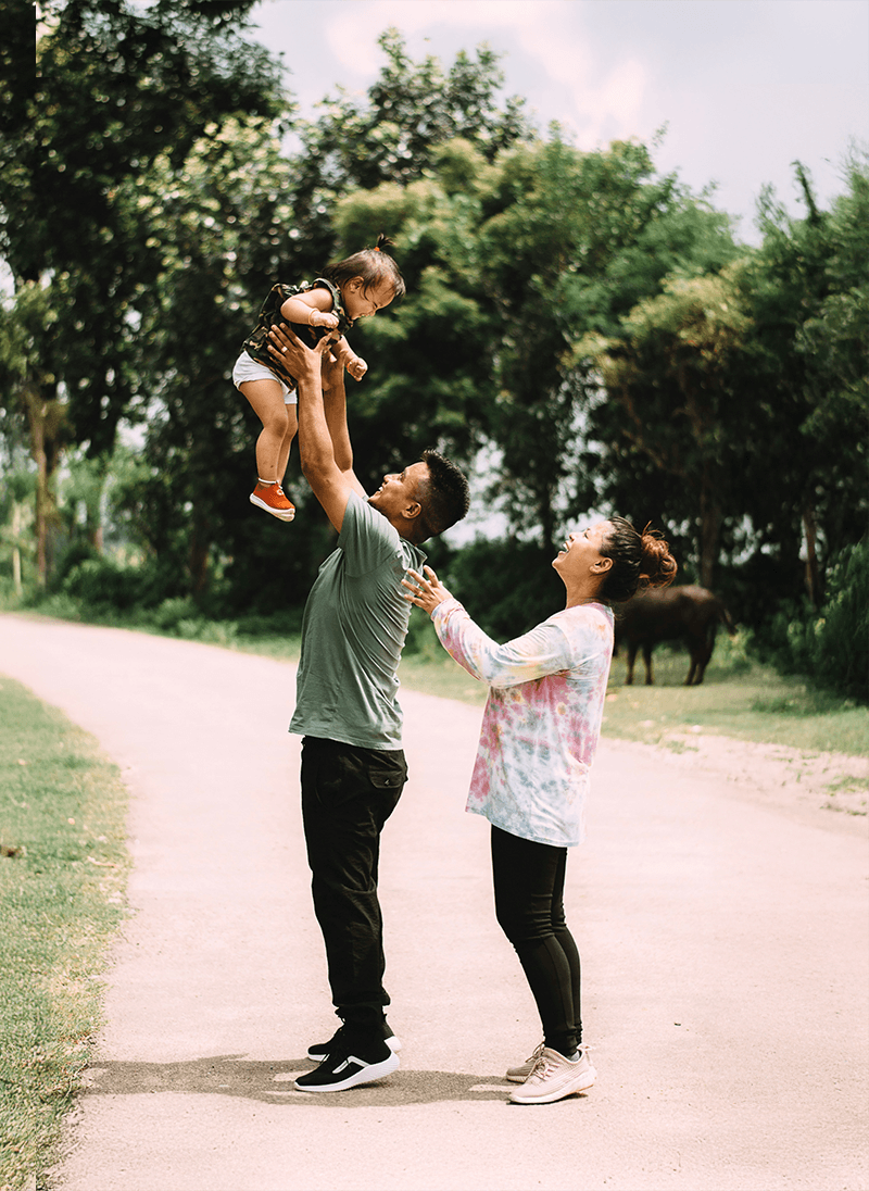 Man holding baby with women in a park on a trail