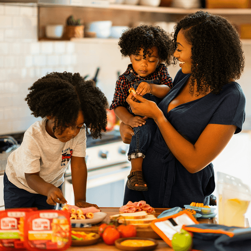 A woman and two children making lunch in a kitchen.