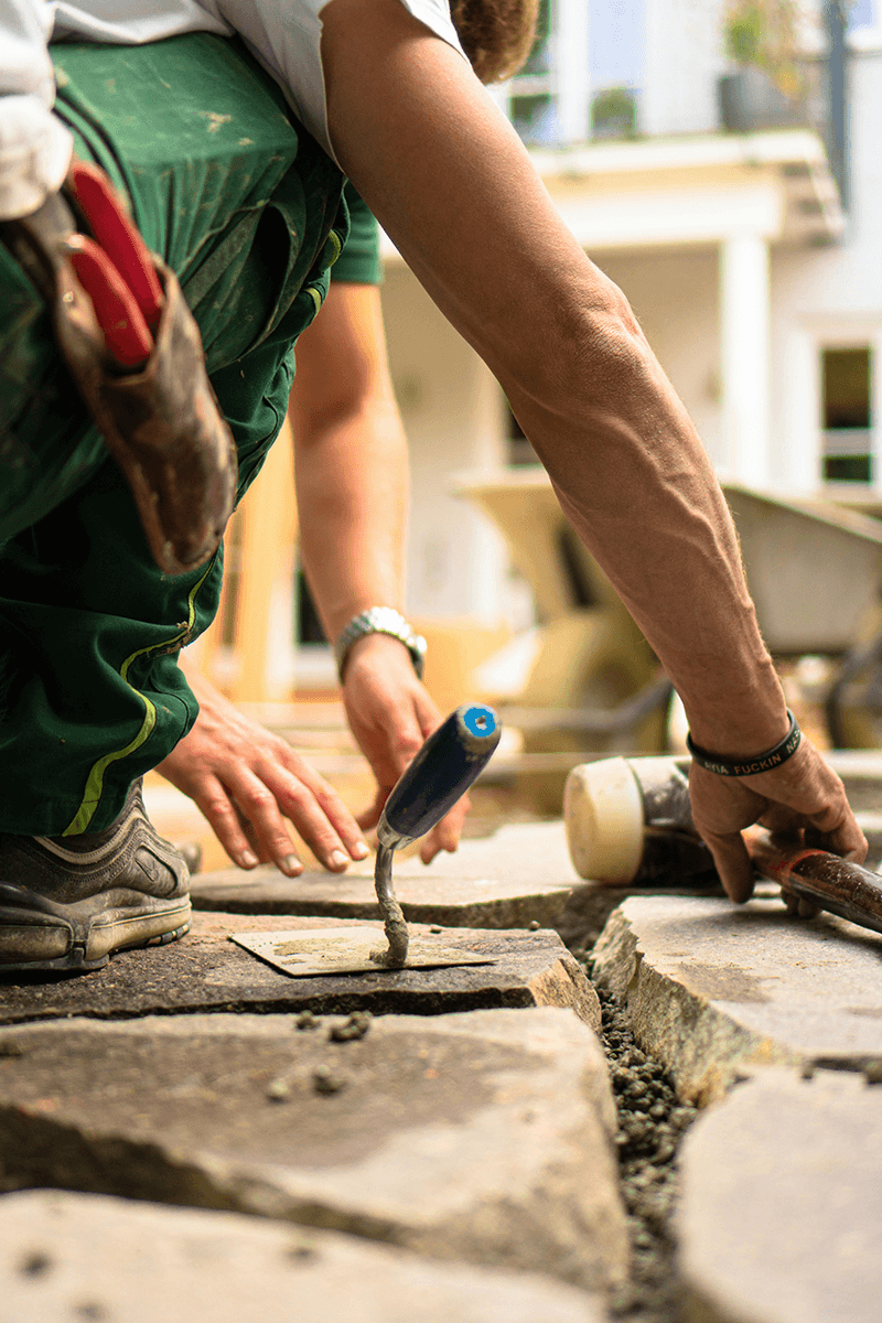 Person in green pants making a stone walkway.