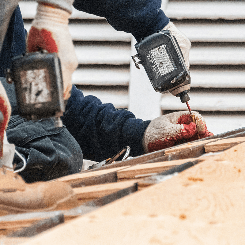 Person using a cordless drill with screws on a roof. 